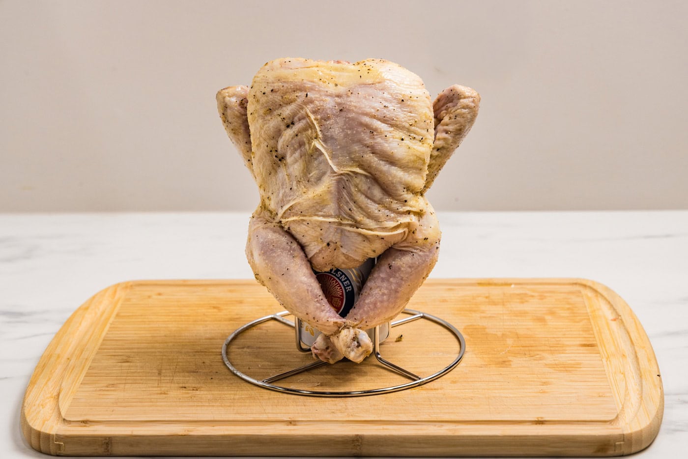raw chicken on beer can chicken holder