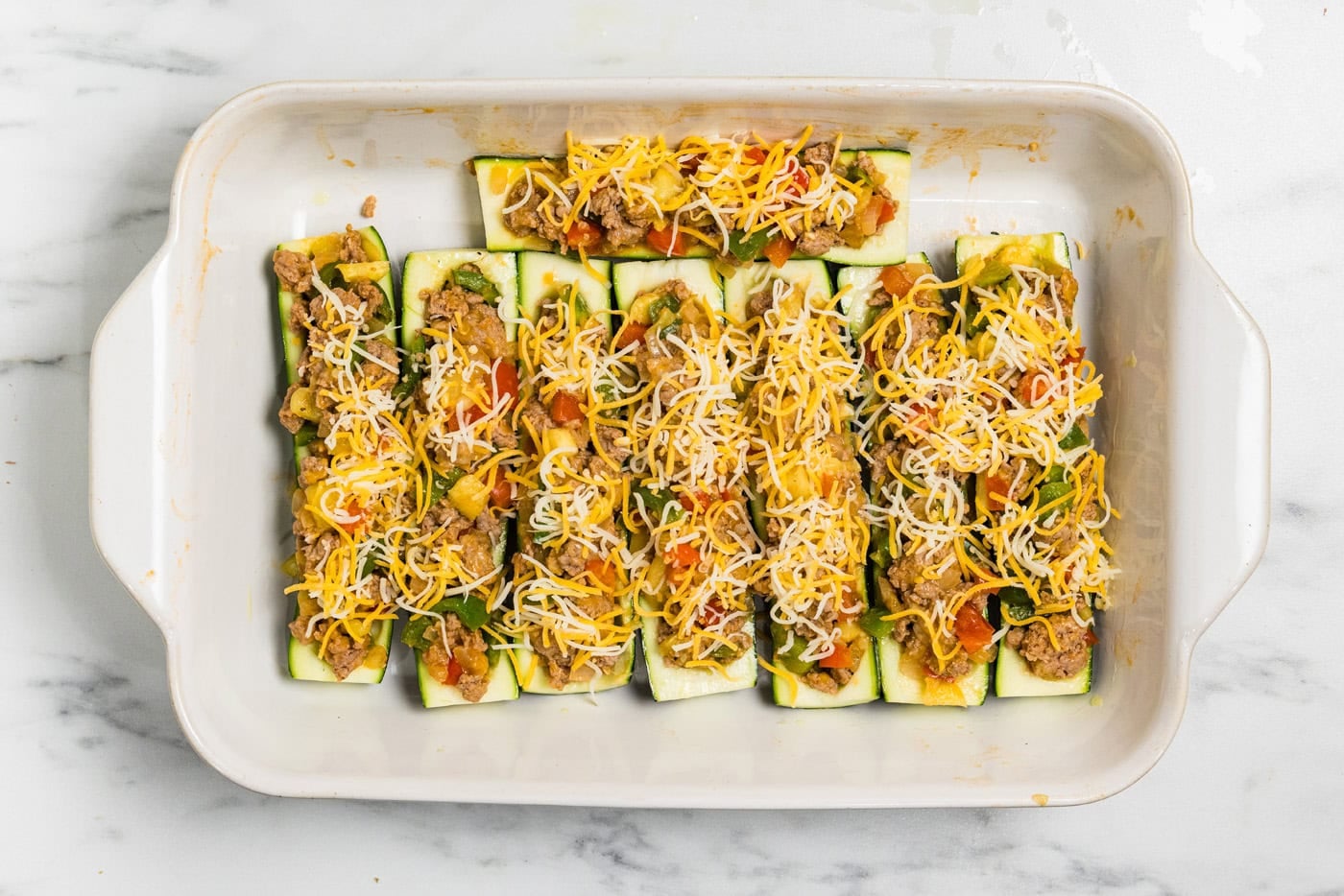 Stuffed zucchini boats topped with cheese to go in th oven