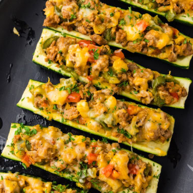 Stuffed zucchini boats lined up on black platter