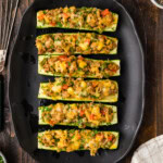 overhead view of Stuffed zucchini boats on black platter