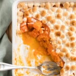 Baked candied yams topped with toasted marshmallows in a white dish.