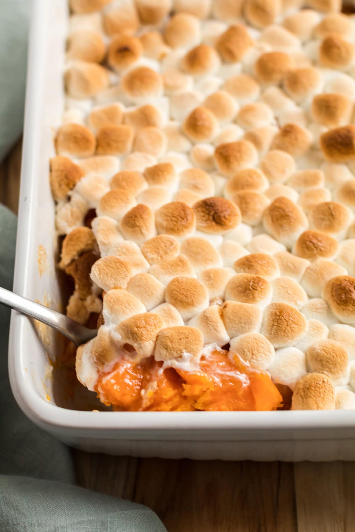 spoon lifting candied yams with marshmallows