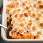 spoon lifting candied yams with marshmallows