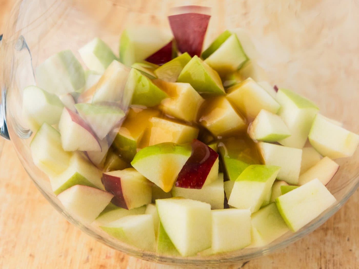 chopped apples in a pitcher with caramel sauce drizzled on top