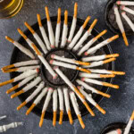 overhead view of Halloween Cigarette Pretzels on a table with drinks and a skeleton hand