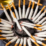 angled shot of Halloween Cigarette Pretzels in a dish of fake edible ashes