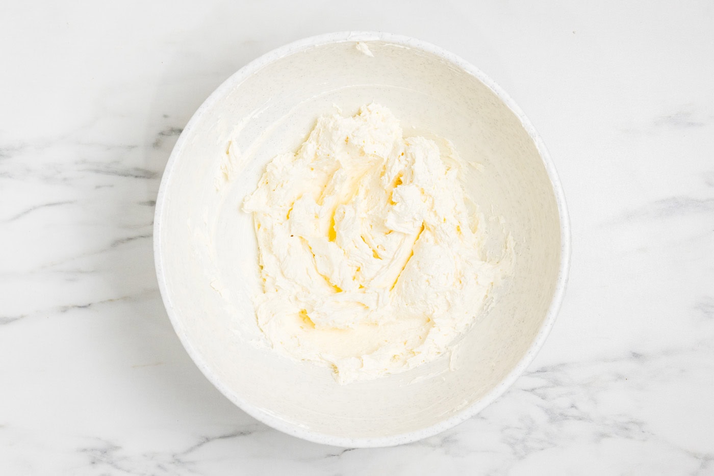 Cream cheese and Cool Whip folded together until smooth in a white bowl