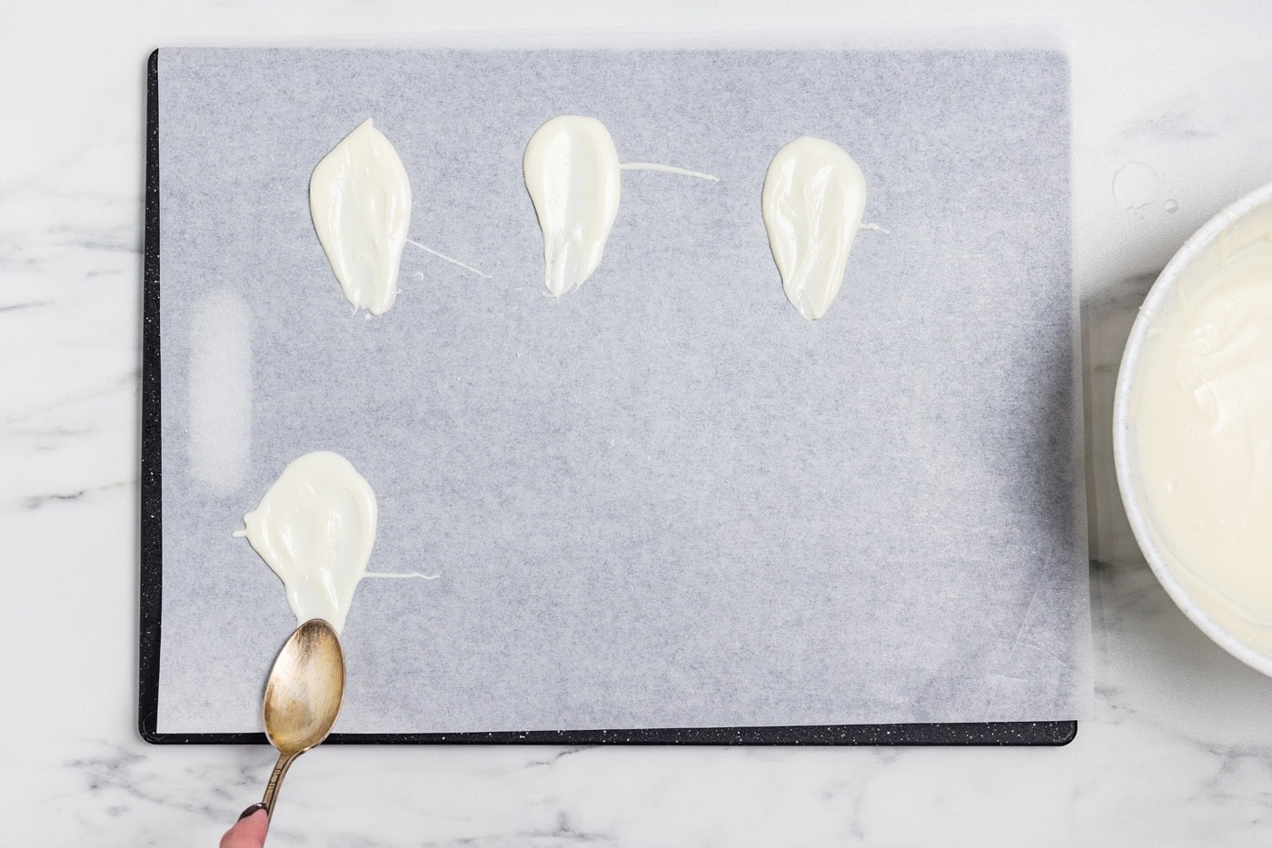 Melted white chocolate spooned onto wax paper and pulled downward into a ghost shape with a lollipop stick laid into it