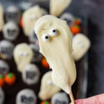 A white chocolate ghost pop held up over the finished Halloween dirt cake