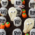 Bloodshot candy eyeballs half buried in Oreo dirt among cookie tombstones and ghosts