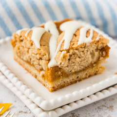 A single pumpkin pie square with cream cheese drizzle on a white scalloped plate