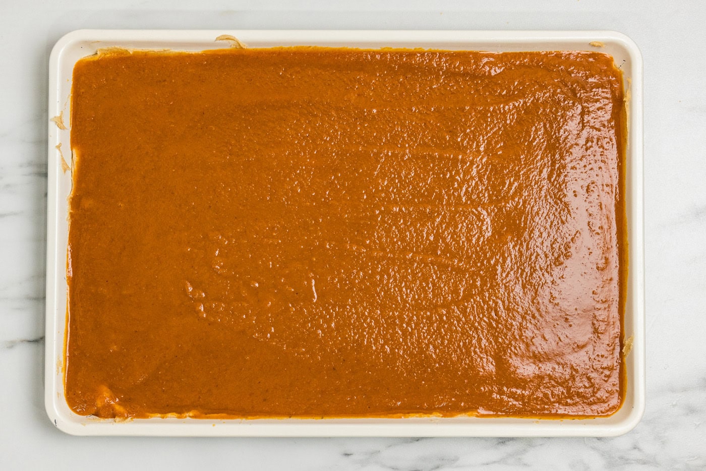 Pumpkin filling spread over the cake batter to the edges of the pan