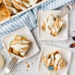 Pumpkin pie squares served on small white plates beside the baking pan with forks and fall leaves