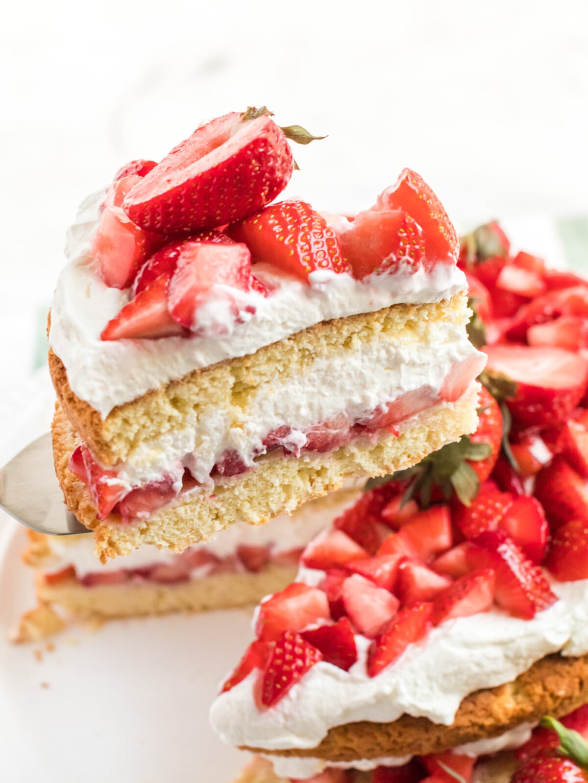 spatula lifting a slice of strawberry shortcake cake