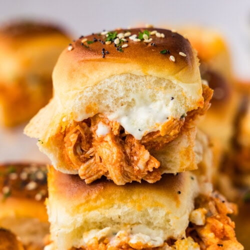 Two buffalo chicken sliders stacked with blue cheese dressing and shredded buffalo chicken on Hawaiian rolls