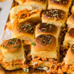 Board of buffalo chicken sliders with saucy shredded chicken and blue cheese crumbles under seeded buns
