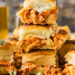 Three buffalo chicken sliders stacked to show shredded buffalo chicken, blue cheese crumbles and blue cheese dressing