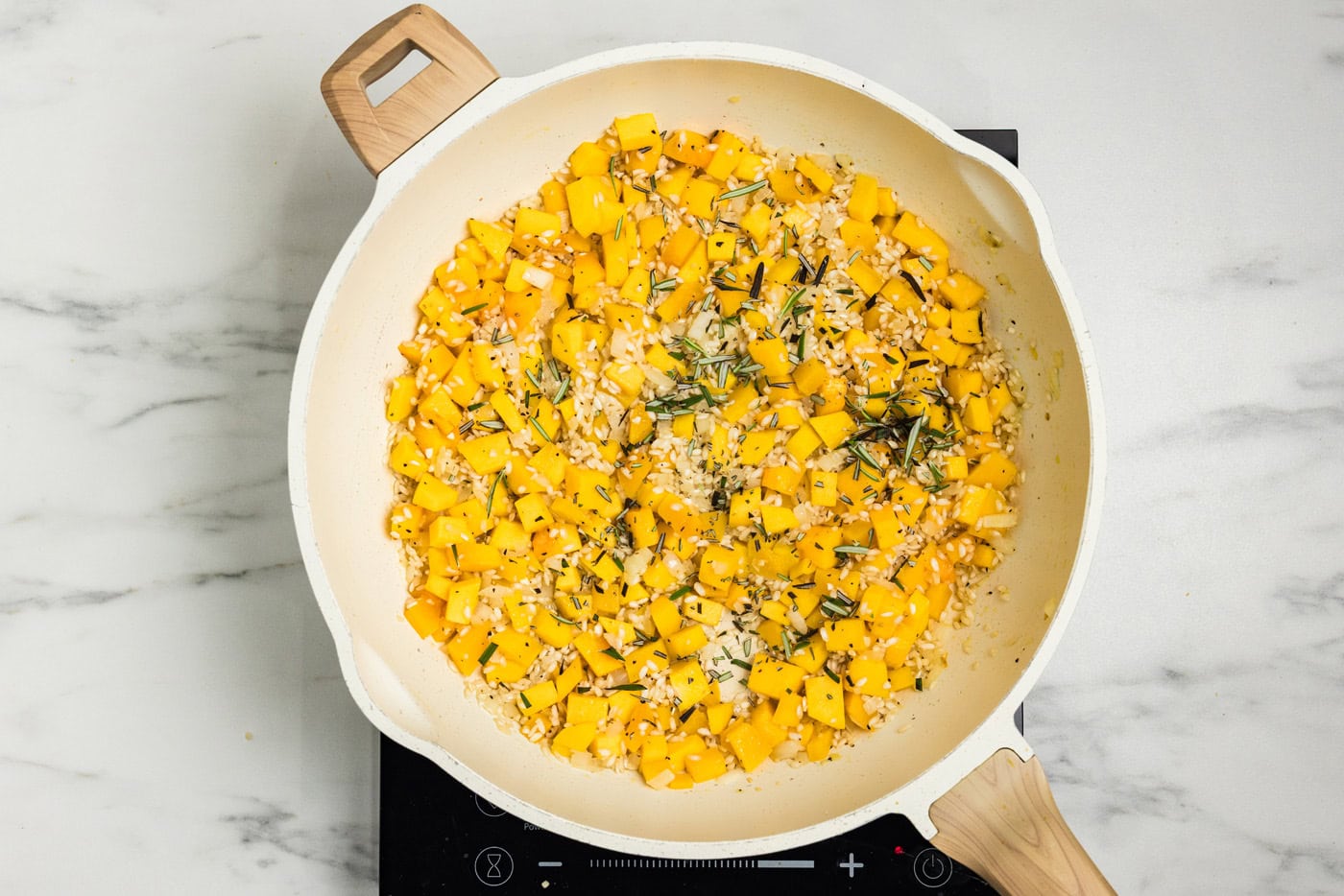 Fresh rosemary and minced garlic stirred into the rice and butternut squash in the skillet.