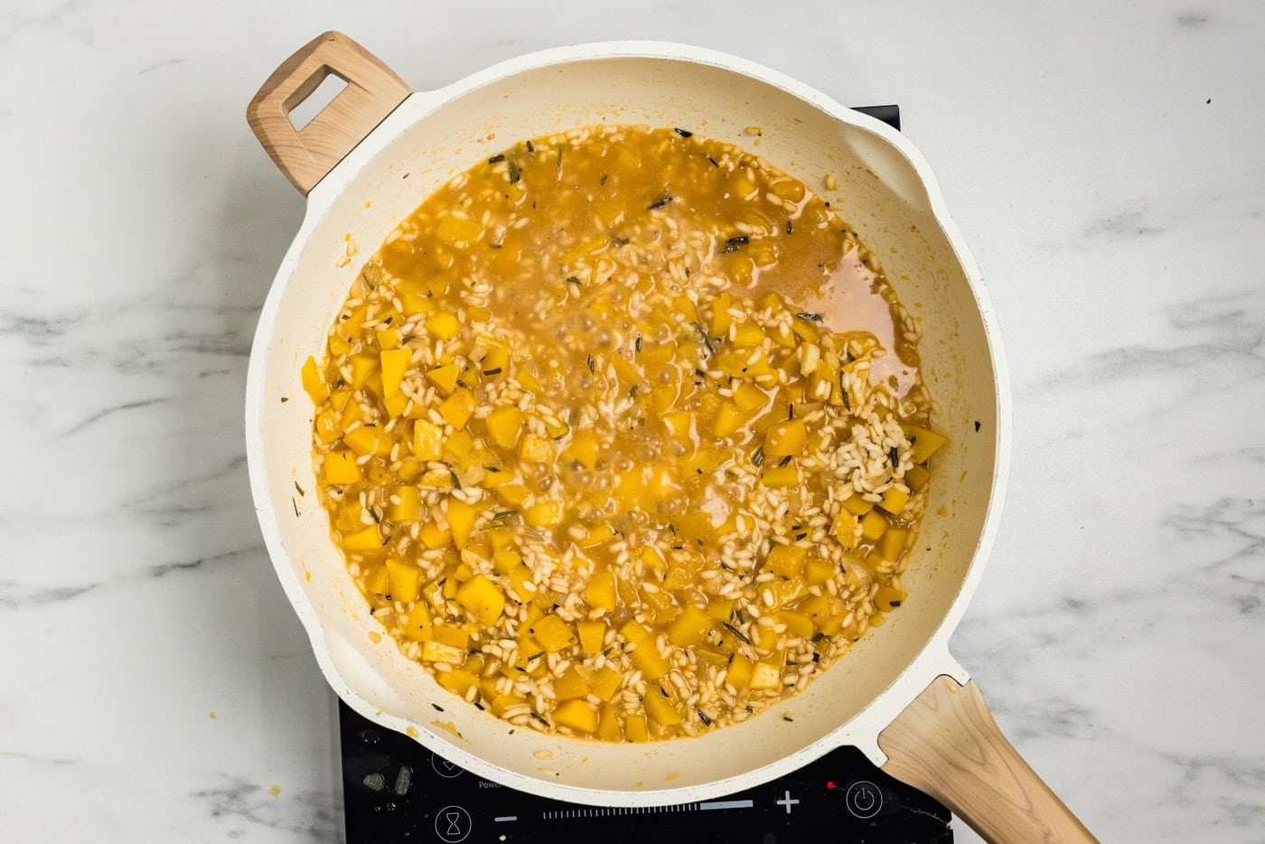 Creamy butternut squash risotto nearly finished cooking in the skillet.