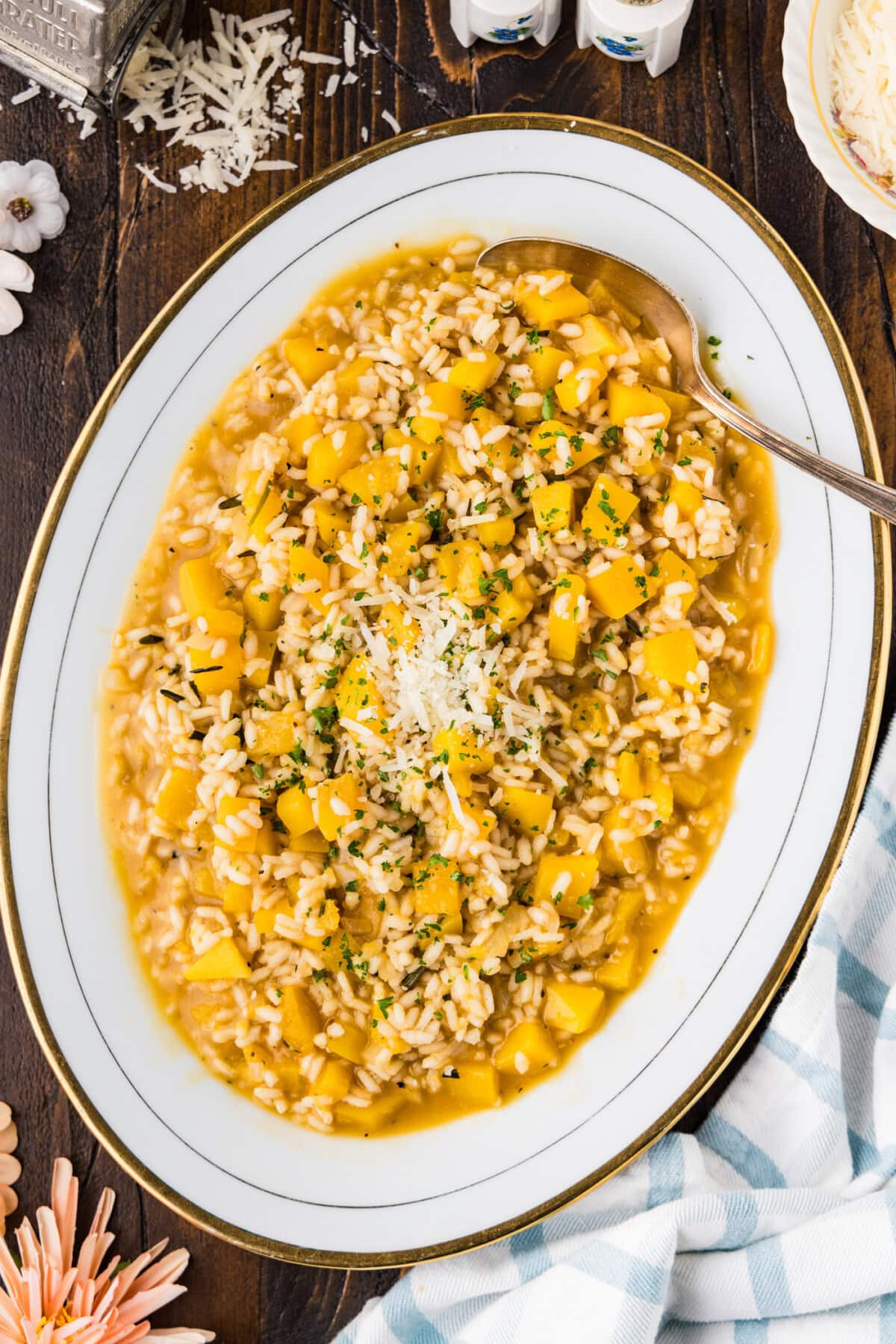 Butternut squash risotto on an oval serving platter topped with grated Parmesan and parsley.