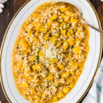 Butternut squash risotto on an oval serving platter topped with grated Parmesan and parsley.