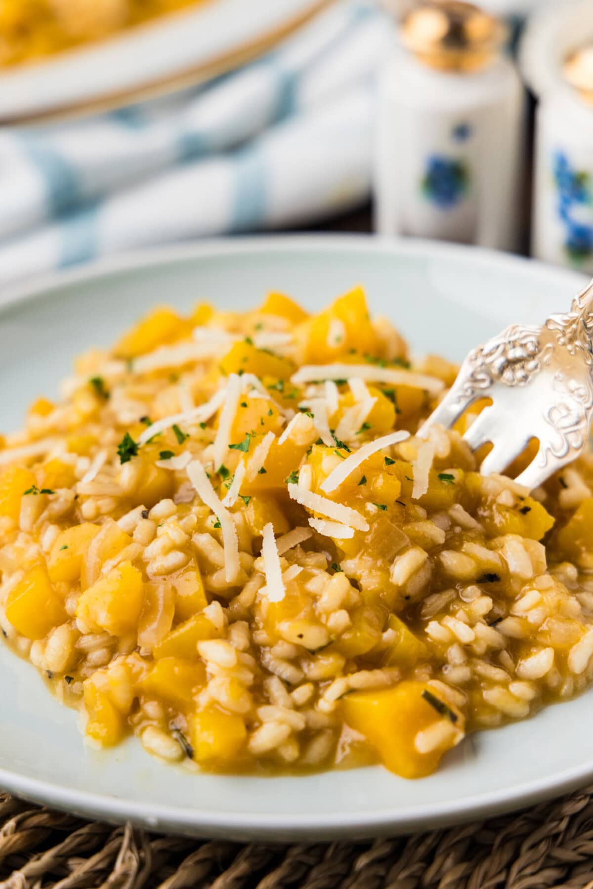 Close-up of creamy butternut squash risotto with shredded Parmesan and a fork on a plate.