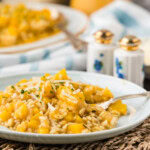 A plate of butternut squash risotto on a woven placemat with the serving platter in the background.