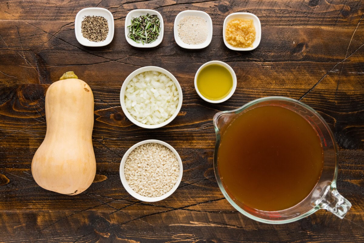 Ingredients for butternut squash risotto, including a whole butternut squash, diced onion, Arborio rice, olive oil, vegetable broth, black pepper, fresh rosemary, garlic salt, and minced garlic.